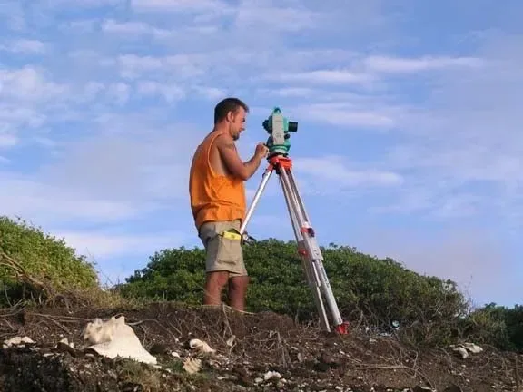 Erik Lash operating a total station on a rocky coastal ridge during a field survey